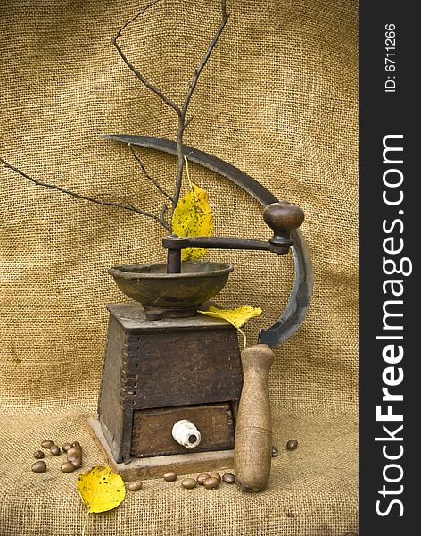 A coffee mill and a sickle in the autumn mood of harvest. A coffee mill and a sickle in the autumn mood of harvest