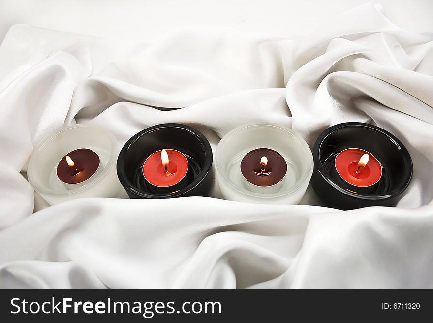 Candles in candlesticks on white silk