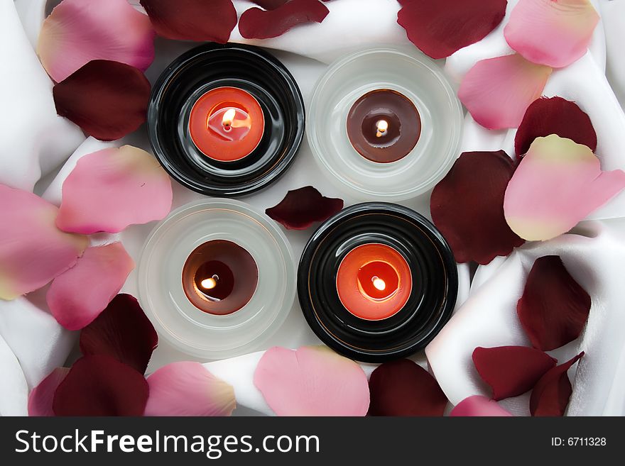 Candles on white silk with petals