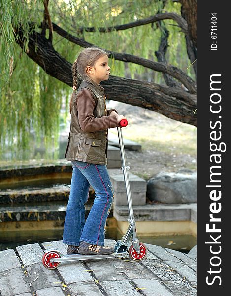 Little girl with scooter staying fon the footbridge. Little girl with scooter staying fon the footbridge