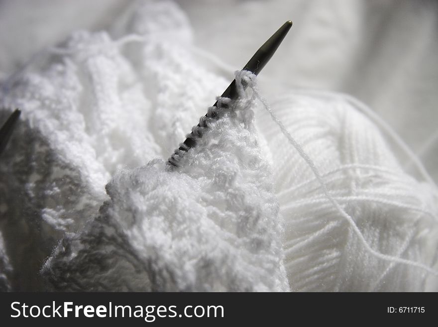 White wool and knitting with needles sticking out creating a shadow. White wool and knitting with needles sticking out creating a shadow