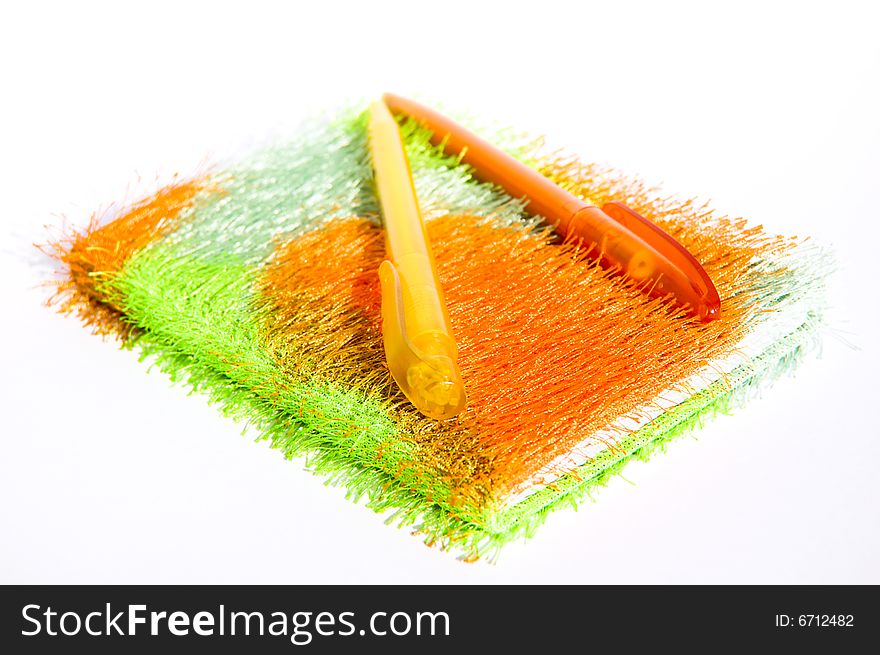 Notebook made of soft fabric with colorful pens on it, isolated on white background. Notebook made of soft fabric with colorful pens on it, isolated on white background