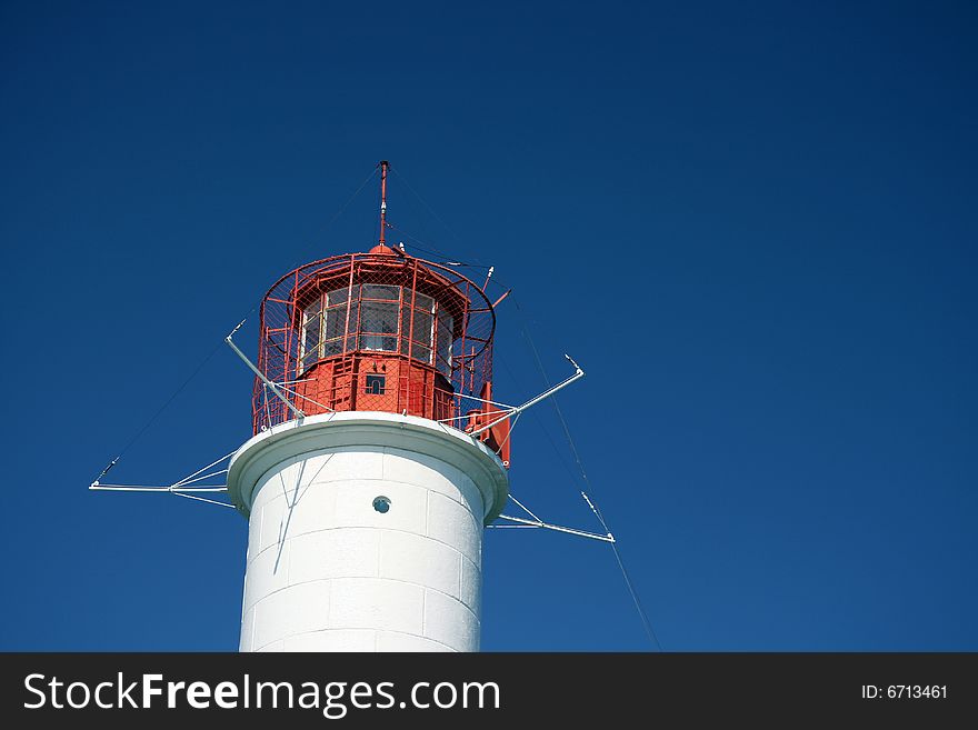 A red and white lighthouse in a clear sky