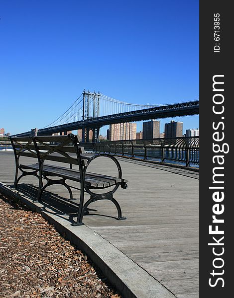 Park bench along the East River in Brooklyn.  Manhattan Bridge in the background. Park bench along the East River in Brooklyn.  Manhattan Bridge in the background.