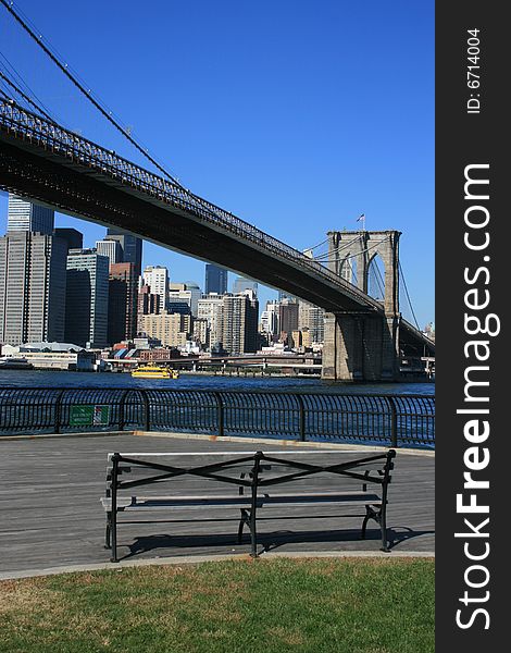 Park bench along the East River in Brooklyn. Lower Manhattan and Brooklyn Bridge in the background. Park bench along the East River in Brooklyn. Lower Manhattan and Brooklyn Bridge in the background.