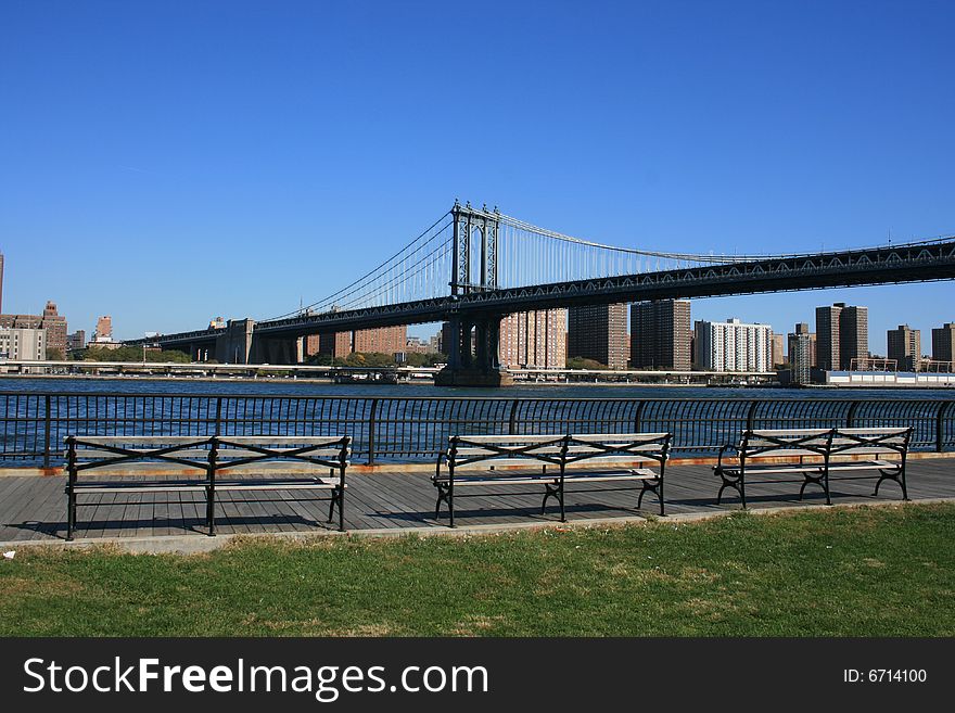 Park benches along the East River in Brooklyn. Manhattan Bridge in the background.