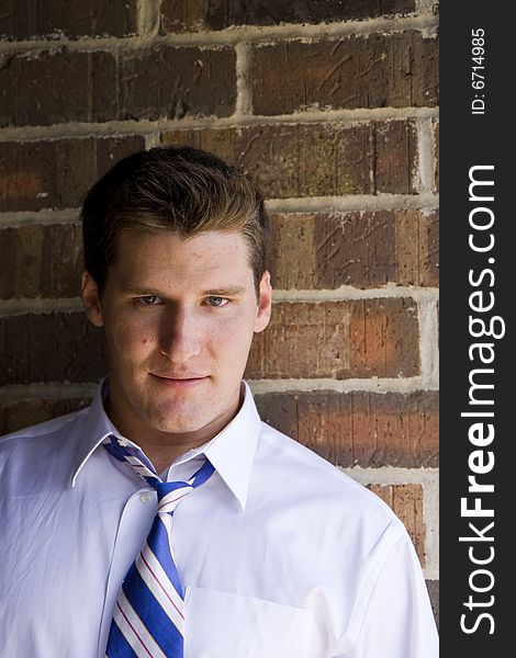 A casual young man leaning against a brick wall. A casual young man leaning against a brick wall