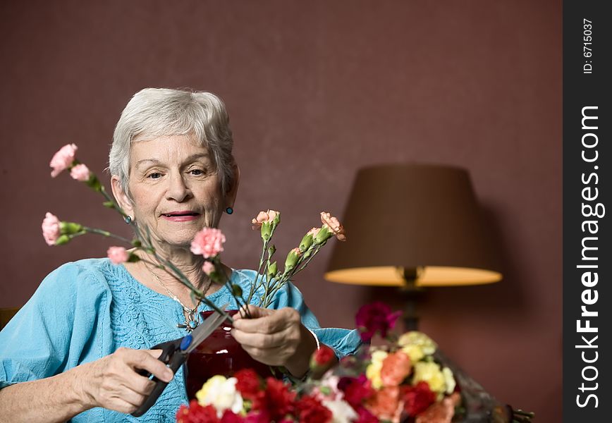 Senior woman at home with colorful flowers. Senior woman at home with colorful flowers