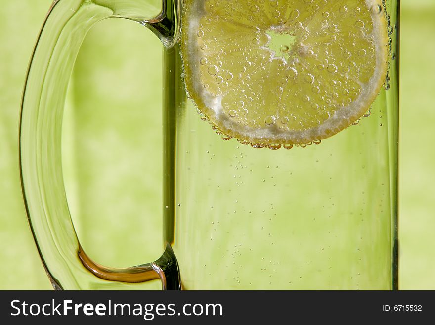 Lemon slice floating in a transparent glass full with sparkling water (club soda). Lemon slice floating in a transparent glass full with sparkling water (club soda)