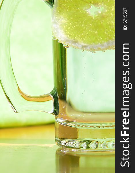 Lemon slice floating in a transparent glass full with sparkling water (club soda). Lemon slice floating in a transparent glass full with sparkling water (club soda)