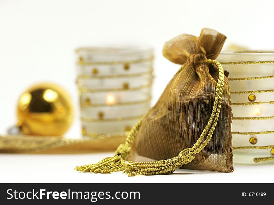 Golden gift bag, ornament and votive on white background