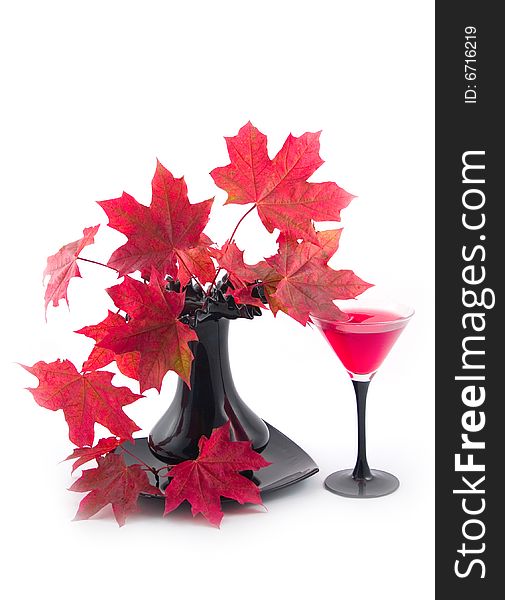 Beautiful red autumn leaves of maple and glass with red wine on white background