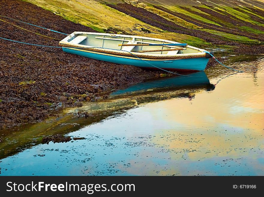 Wooden rowing boat tied near harbour bank at low tide,cornwall, UK. Wooden rowing boat tied near harbour bank at low tide,cornwall, UK.