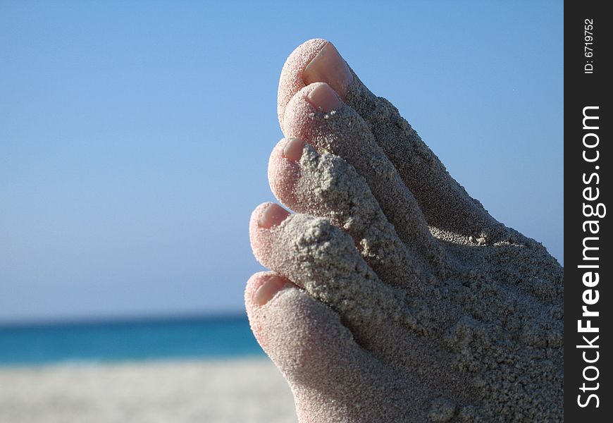 Female foot covered with sand