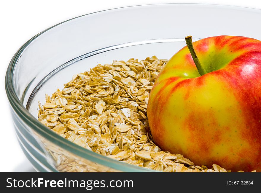 Apple on oat flakes background in a glass bowl &#x28;front view&#x29;. Red, Beige, White, Yellow, colors