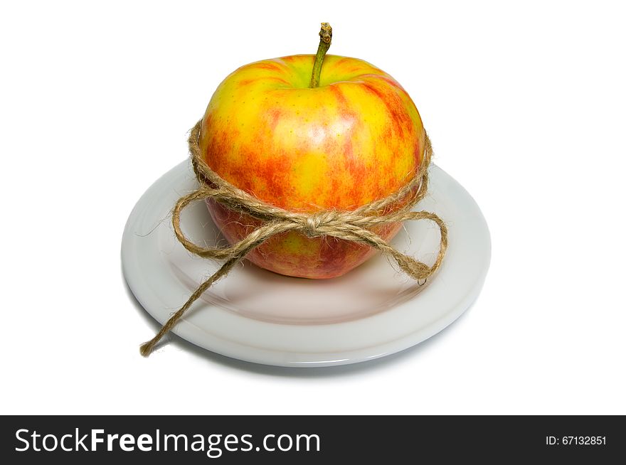 Apple tied with twine on a white plate closeup. Red, Beige, White, Yellow, colors