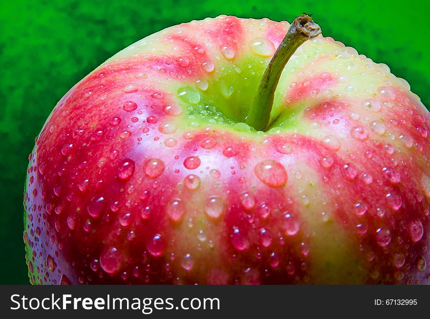 Drops of water on an apple closeup on a dark green textured background. Drops of water on an apple closeup on a dark green textured background