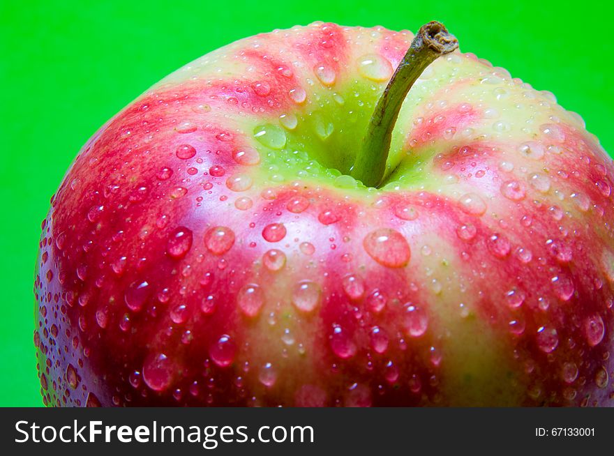 Drops of water on an apple closeup on a green background