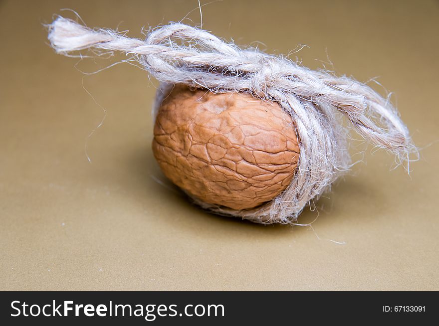 Walnut tied with twine on a brown background front light