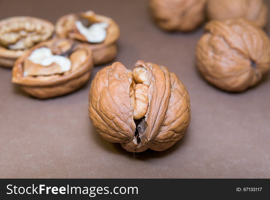 Cracked walnut in the middle on the background of other walnuts &#x28;gray shade&#x29;. Cracked walnut in the middle on the background of other walnuts &#x28;gray shade&#x29;