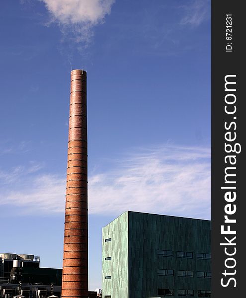 A singular brick steam stack in front of a blue sky. A singular brick steam stack in front of a blue sky
