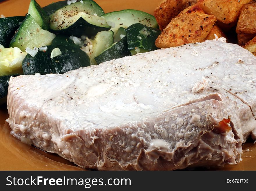 This is a close up image of a tuna filet, potatoes, and vegetables.