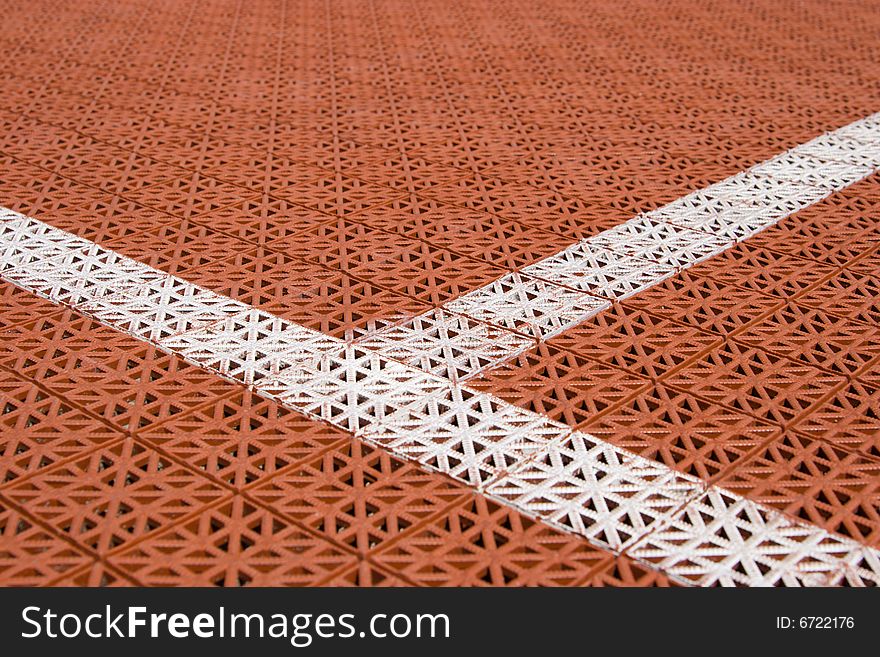 Artificial tennis court cover, brown with white lines, close-up