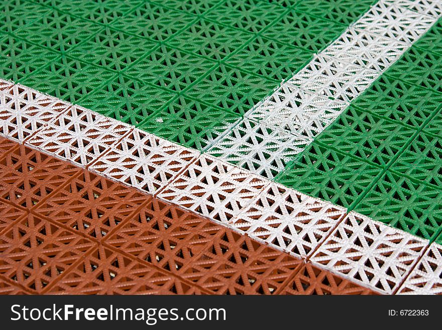 Artificial tennis court cover, brown and green with white lines, close-up