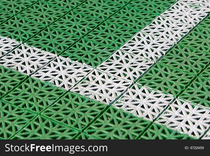 Artificial tennis court cover, green with white lines, close-up