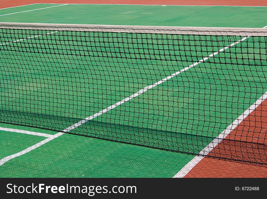 Green and brown tennis court with a net