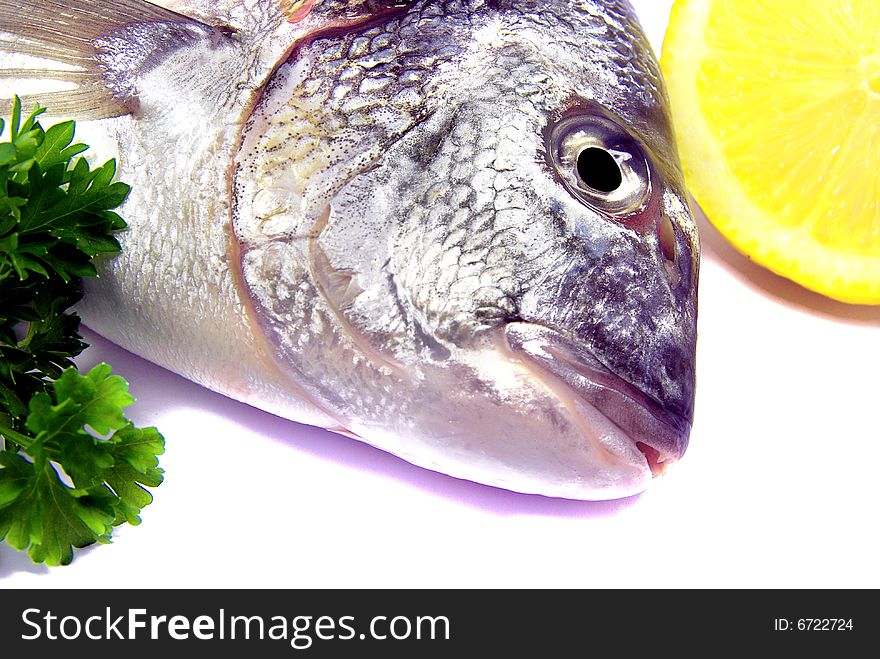 Detail view of a raw sea bream with parsley and lemon. Detail view of a raw sea bream with parsley and lemon.