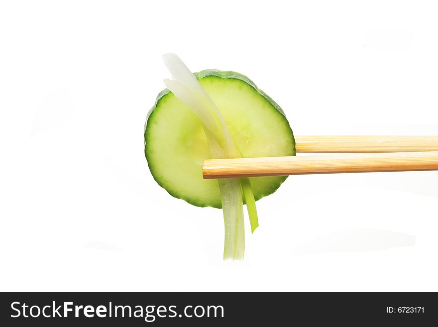 Cucumber and spring onion in chopsticks against white