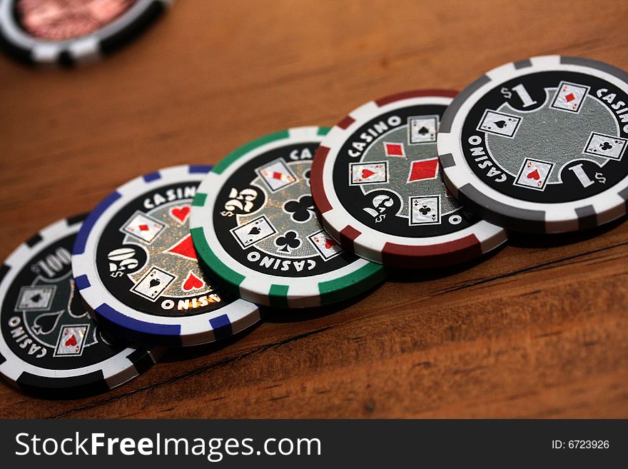 Poker chips in different colours on a brown table. Poker chips in different colours on a brown table