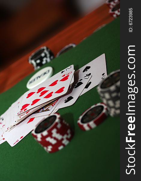 Poker chips in different colours on green background with playing cards. Poker chips in different colours on green background with playing cards