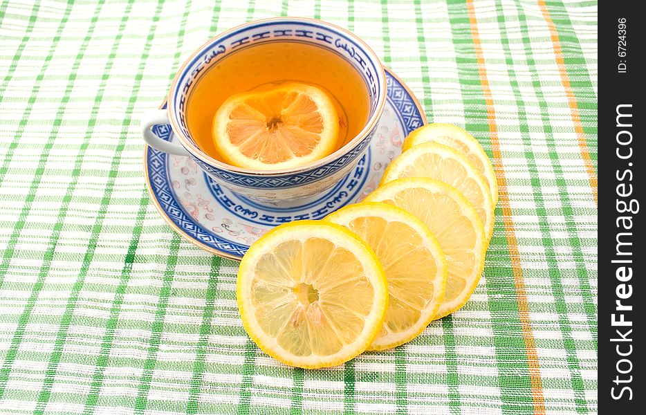 Fragrant tasty useful tea with lemon cup with blue figure on napkin green strip. Fragrant tasty useful tea with lemon cup with blue figure on napkin green strip