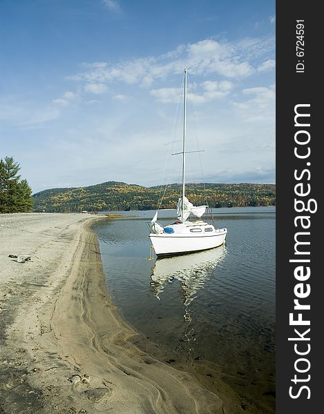 A small white sail boat near the shore