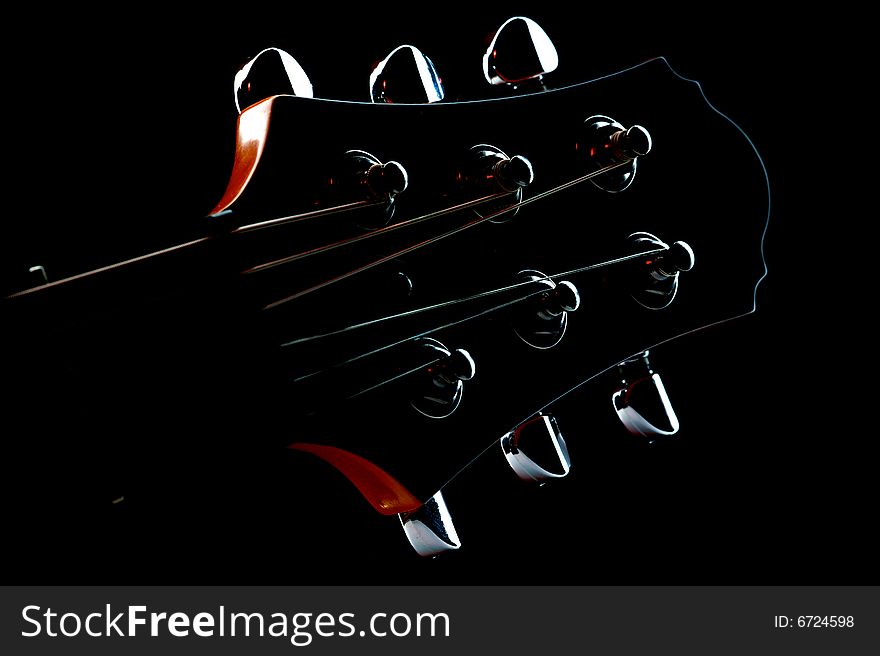 Guitar head stock on black background with red reflexes