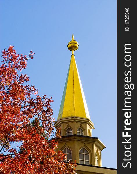 A picture of a building with a golden roof and a treen in autumn red. A picture of a building with a golden roof and a treen in autumn red