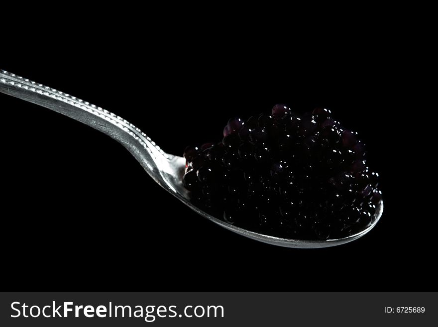 Black  lumpfish caviar roe in a spoon on black background. Black  lumpfish caviar roe in a spoon on black background