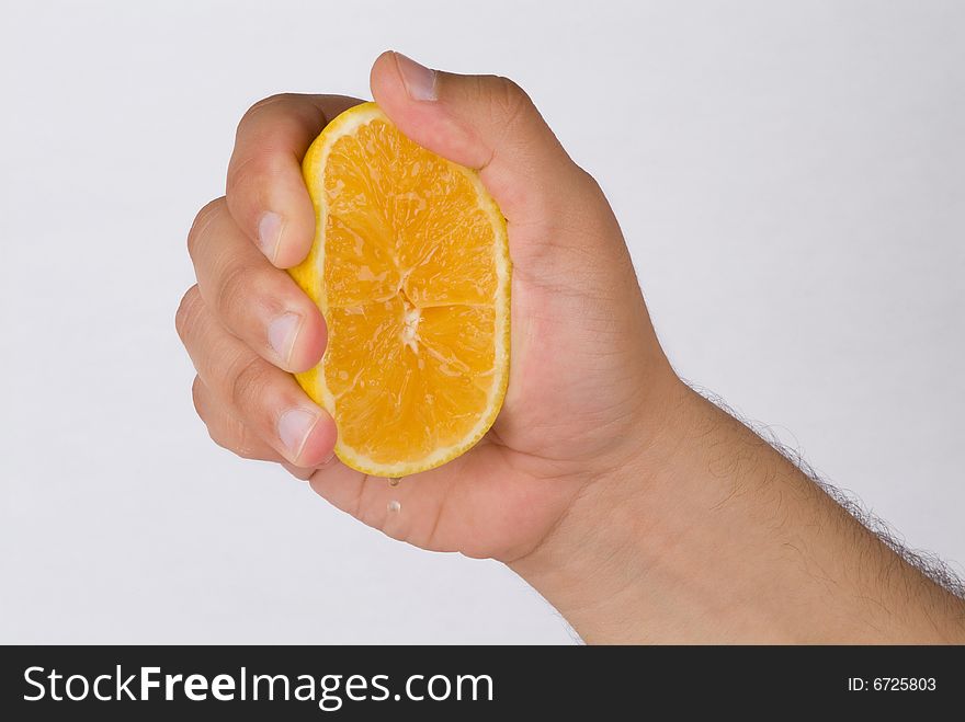 A hand squeezing for orange drops. A hand squeezing for orange drops