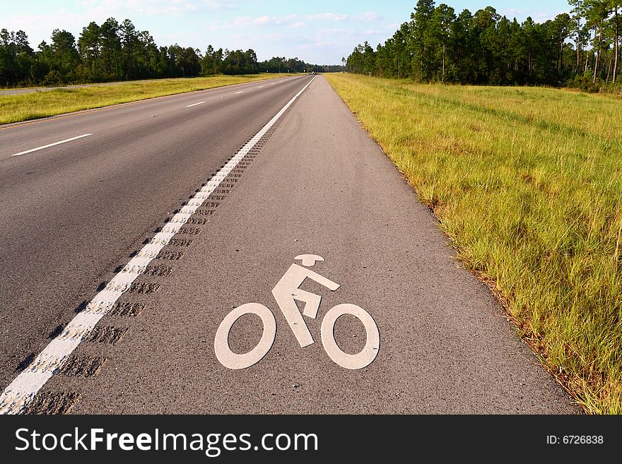 Bicycle lane on a long straight highway with a graphic of a stick man on a stick bike.