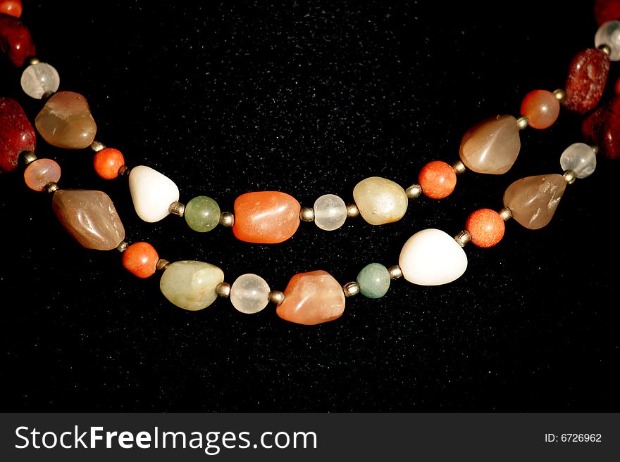 Necklaces of different precious stones on black background