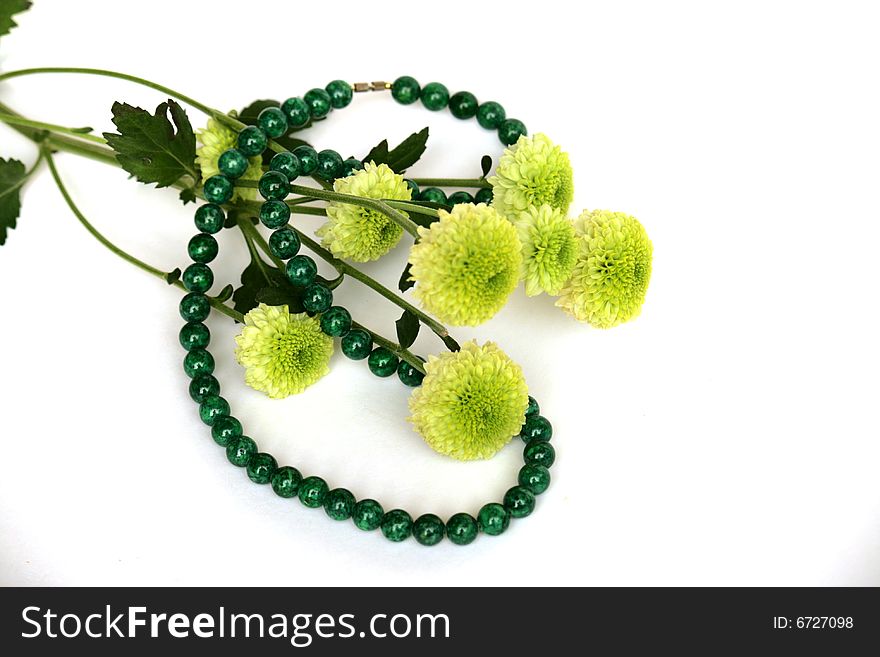 Malachite necklace and flowers on white background