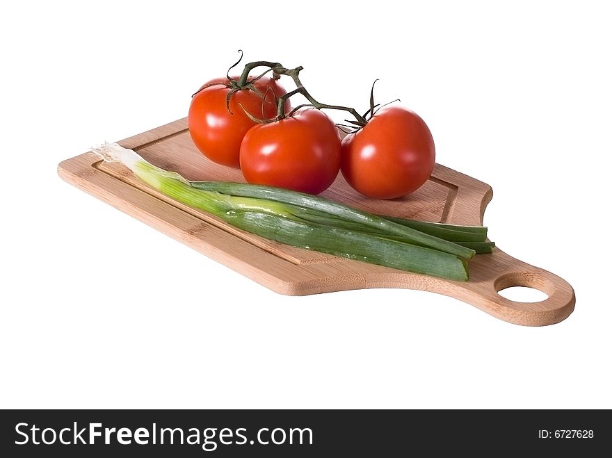 Three tomatoes on the vine and green onions displayed on a bamboo cutting board. Three tomatoes on the vine and green onions displayed on a bamboo cutting board