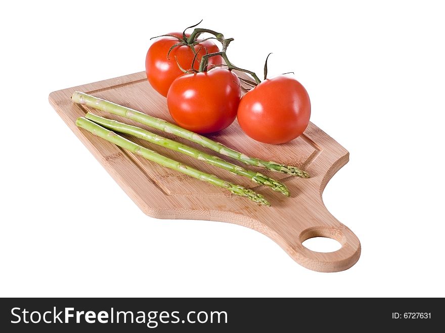Vine tomatoes and asparagus arranged on bamboo cutting board