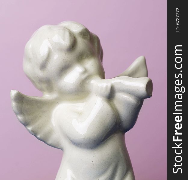 Angel cherub icon statue set against pink background