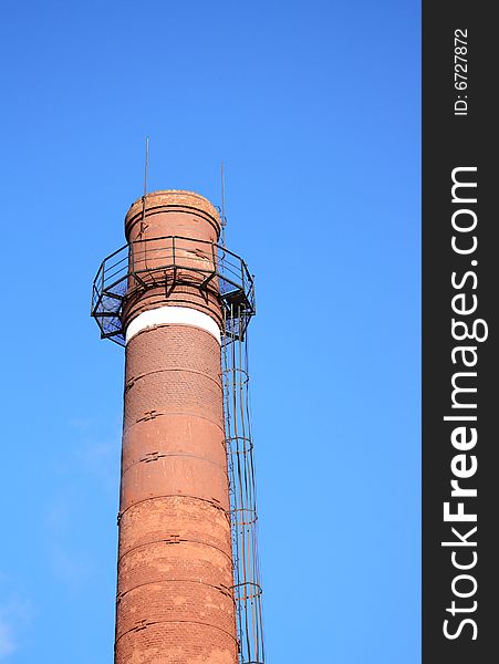 High brick chimney-stack on background with blue sky