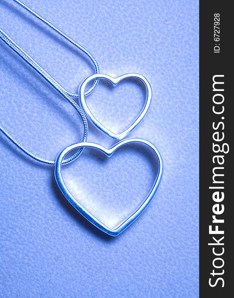 Two hearts with Silvers and necklace isolated on the tint blue. Two hearts with Silvers and necklace isolated on the tint blue.