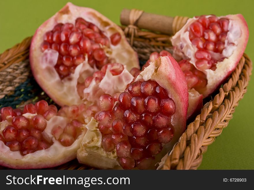 Pomegranate close-up in basket isolated on green background
