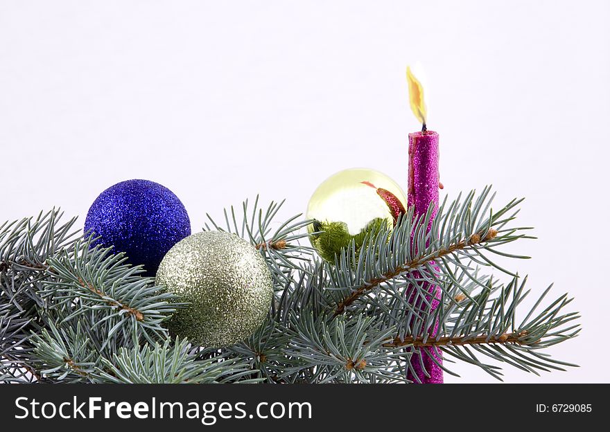 Christmas balls and candle with branches ate on a white background